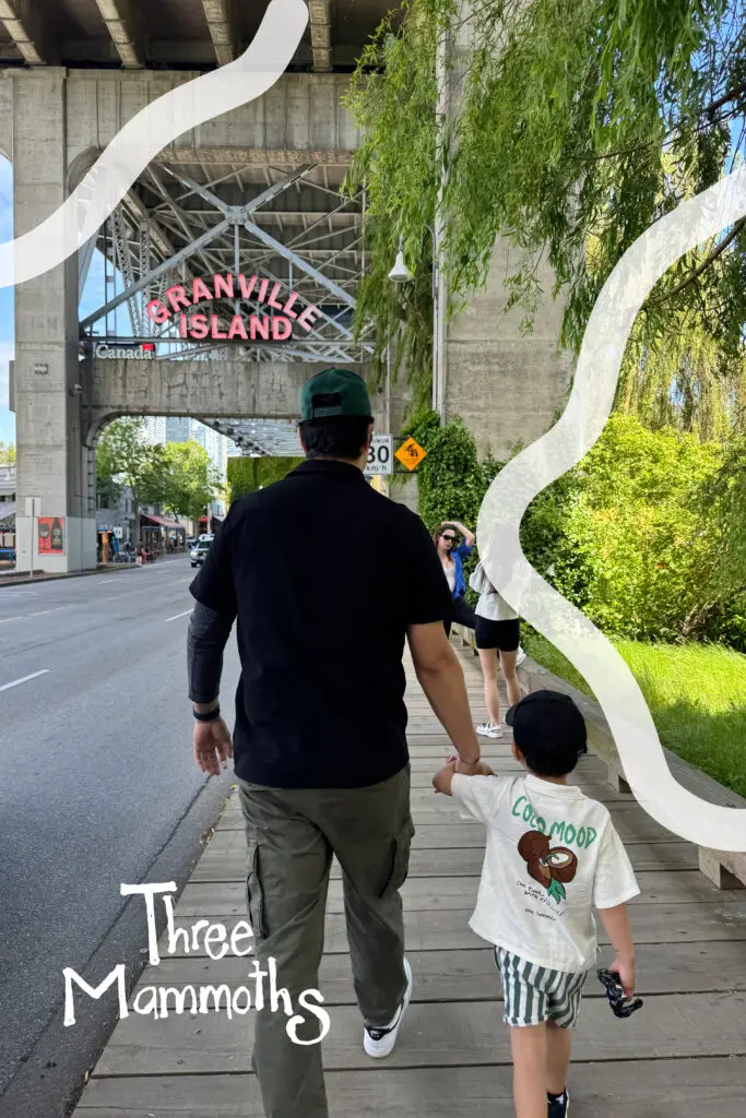 kid and dad walking under the graville island bridge on a summer day